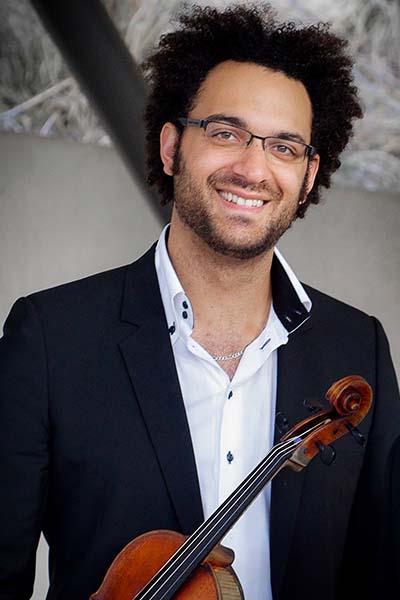 Person wearing a white button up shirt and dark jacket, holding a viola