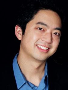 Person wearing a blue collared shirt and dark jacket