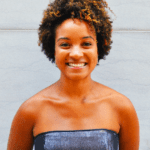 Person with short curly hair wearing a strapless top