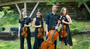 4 people wearing black standing outside holding instruments