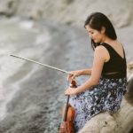 Person sitting on a beach holding a violin