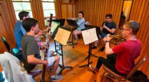 People sitting in a circle playing woodwind instruments